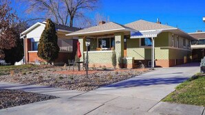 A two-story residential building with a brick facade, a covered front porch, and a small front yard with a gravel path and a single tree.
