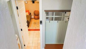 Una escalera que conduce a una habitación con piso de baldosas y una puerta de madera.