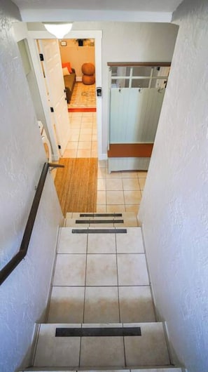 A staircase leading to a room with a tiled floor and a wooden door.
