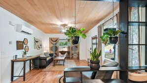 A modern living room with a wooden ceiling, a sofa, a coffee table, and hanging plants.