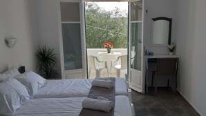 Ein Schlafzimmer mit Bett, Nachttisch, Spiegel und Blick auf einen Balkon mit Tisch und Stühlen.