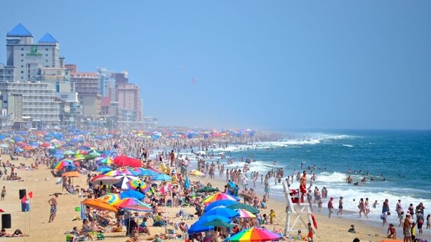 Une plage bondée, avec de nombreux parasols, où les gens profitent de la mer.