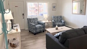 Une pièce comprenant un canapé, deux fauteuils à motifs, une petite table, une lampe et un miroir fixé au mur.