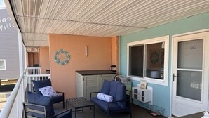 Un balcon avec deux canapés, une petite table et une fenêtre donnant sur la maison.