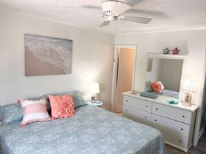Un dormitorio con cama, cómoda, espejo y ventilador de techo.