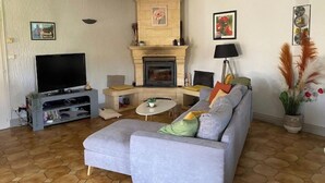 A living room with a fireplace, a television, and a sofa. - Holiday home in Périgord (Saint-Georges-de-Montclard)