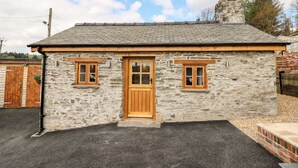 A stone cottage with a wooden door, two windows, and a chimney. - The Old Cobblers Shop (Llandrindod Wells)