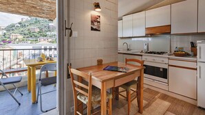 A compact kitchen with a dining area, a view of the city, and a balcony with outdoor seating. - Stunning Sea View Apartment by Wonderful Italy (Camogli)