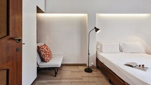 A bedroom with a bed, a chair, a floor lamp, and a door. - Stunning Sea View Apartment by Wonderful Italy (Camogli)