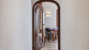A hallway leading to a dining area with a table and chairs, a chandelier, and a wooden door. - Stunning Sea View Apartment by Wonderful Italy (Camogli)