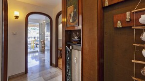 A hallway with wooden doors, a radiator, and a shelf with decorative items. - Stunning Sea View Apartment by Wonderful Italy (Camogli)