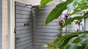 Eine Duschkabine in Eckausführung mit Holzpaneelen, einer Handbrause und einem Wasserhahn.