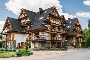 A multi-story hotel with a modern architectural design, featuring balconies and a stone facade.