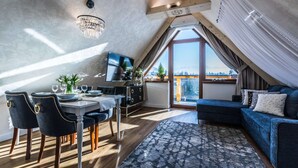 Quarto moderno estilo loft com área de jantar, sofá e uma grande janela com vista.
