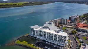 Un hôtel moderne à plusieurs étages, doté d’un parking et offrant une vue sur une rivière.