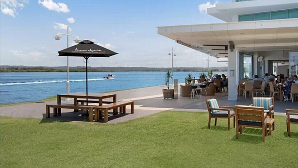 Une terrasse au bord de l’eau, avec des sièges extérieurs et une vue sur le plan d’eau.