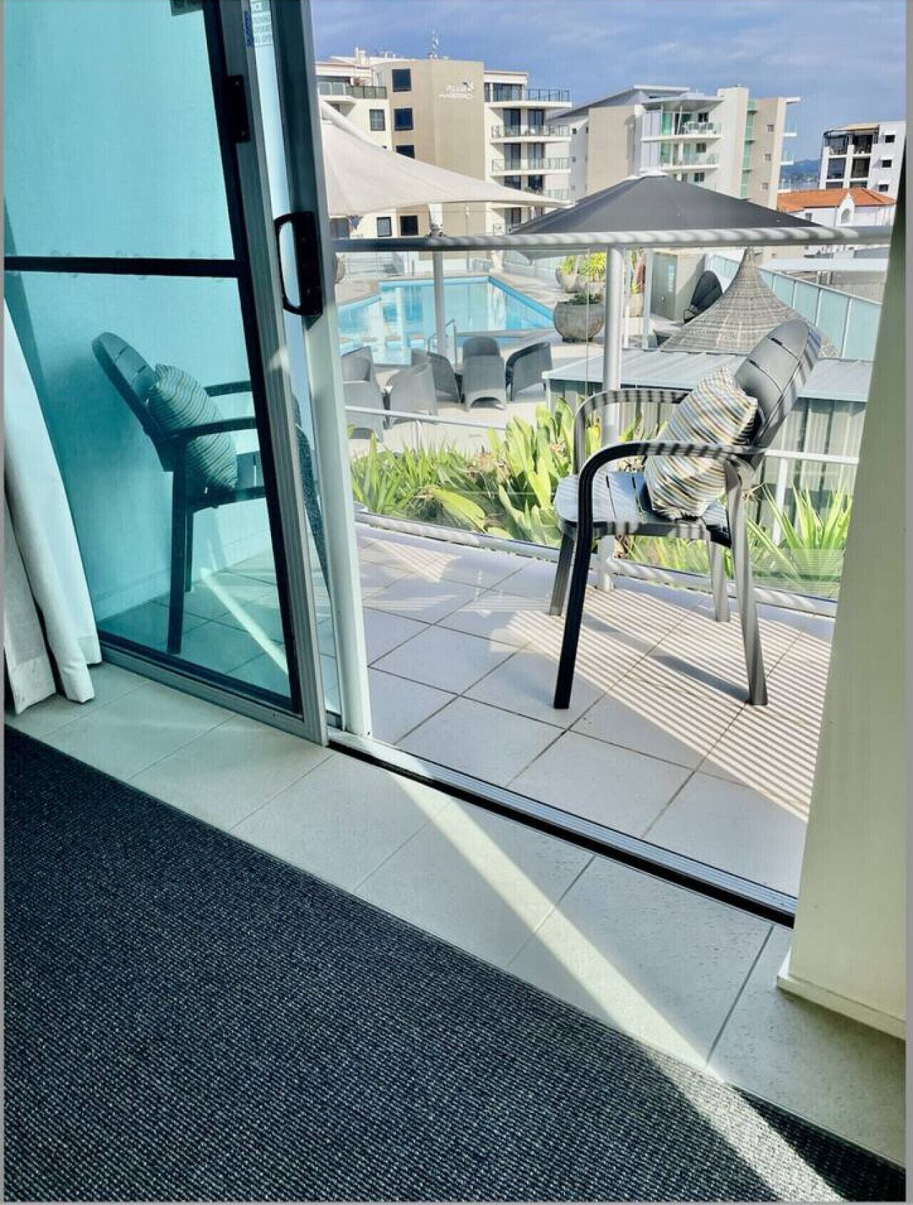 Un balcone con una porta vetrata, una piscina e un'area relax all'aperto.