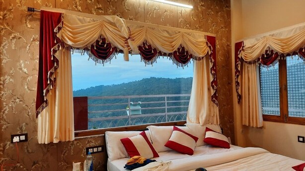 A bedroom with a bed, curtains, and a view of a mountainous landscape. - The Ranikhet Continental (Ranikhet)