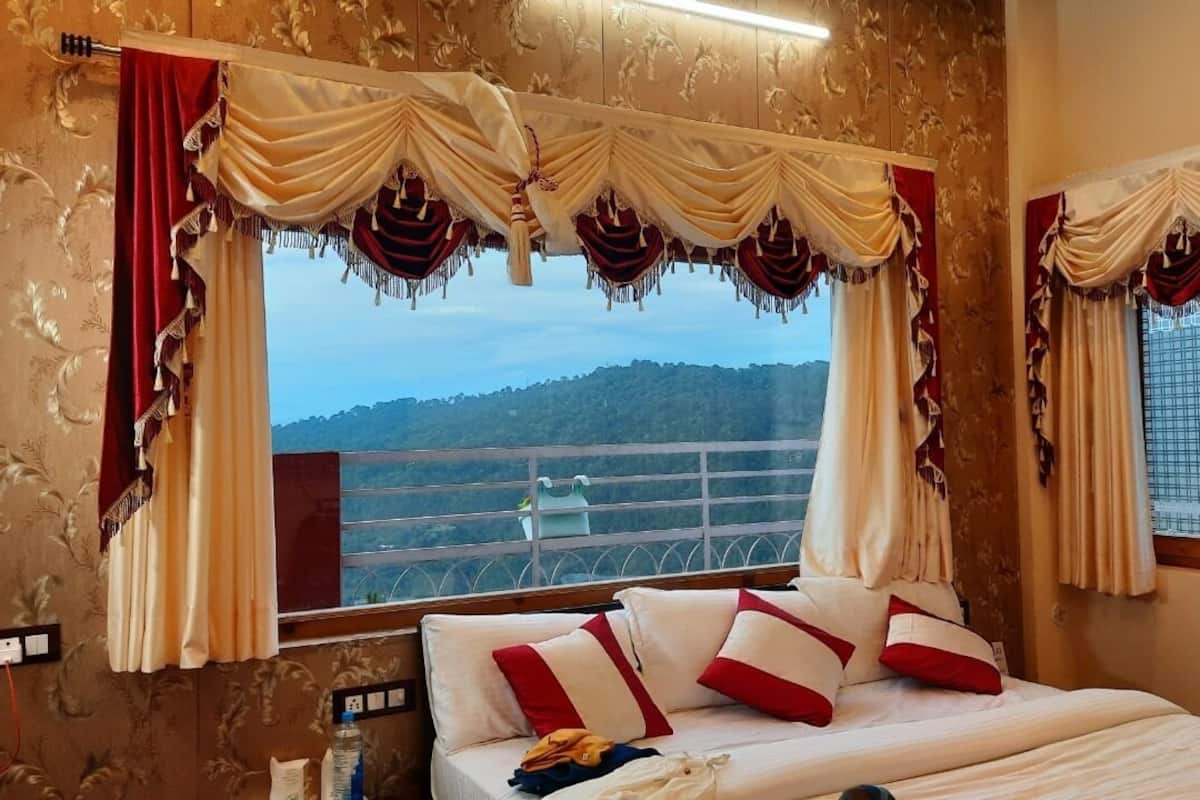 A bedroom with a bed, curtains, and a view of a mountainous landscape.