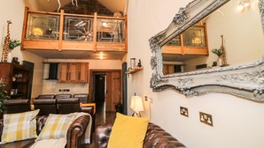 A spacious living area with a high ceiling, a large mirror, and a cozy seating arrangement. - The Upper Room (Ballymena)