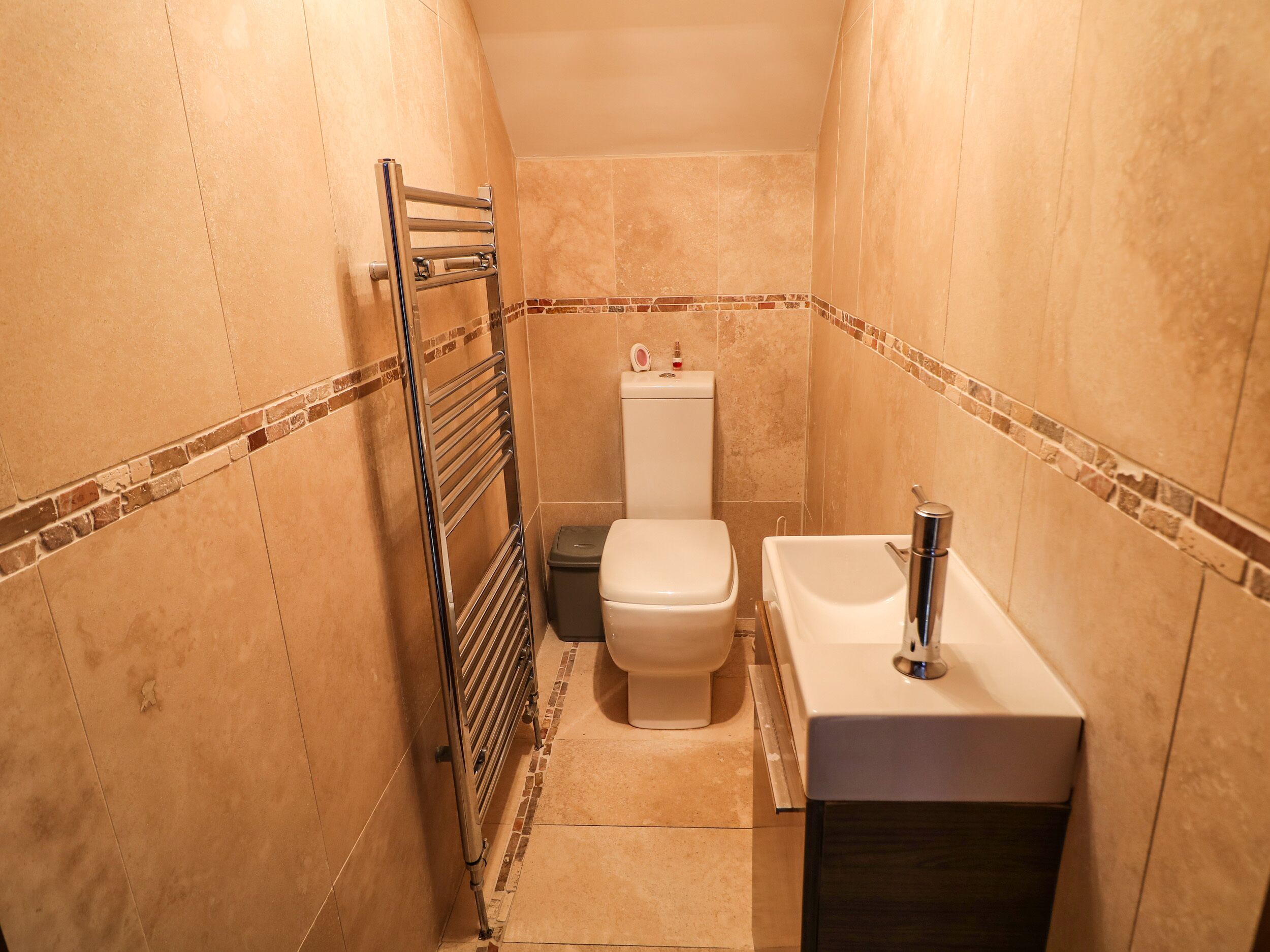 A small, compact bathroom with a toilet, sink, and towel rack.