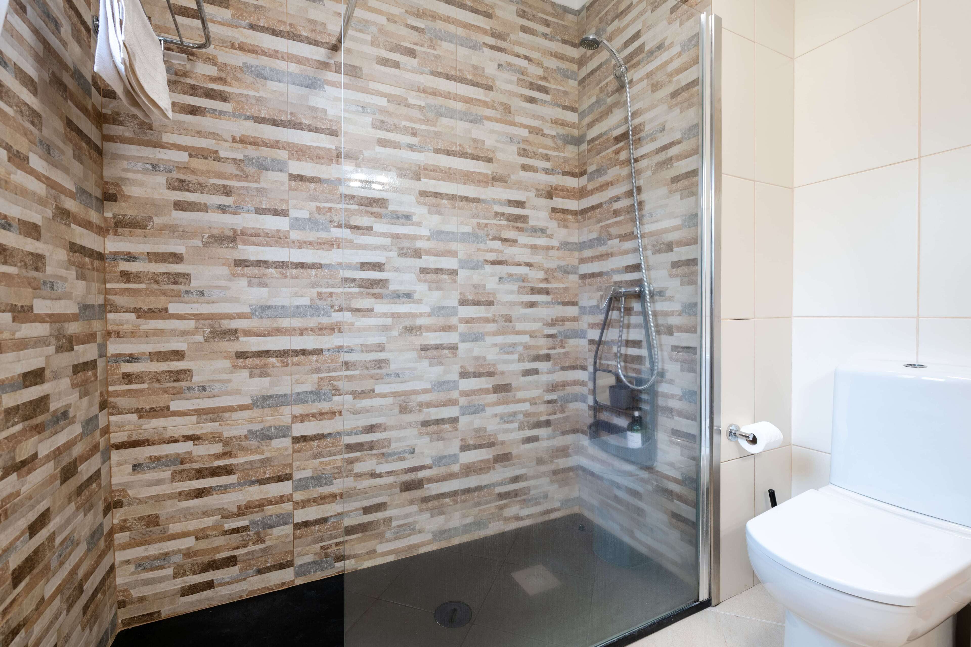 A modern bathroom with a shower area, a toilet, and a glass-enclosed shower stall.