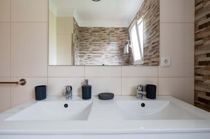 Un baño con dos lavamanos, un espejo y una ventana.