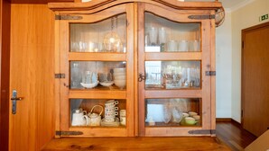 Un meuble en bois doté de portes en verre, renfermant divers ustensiles de cuisine.