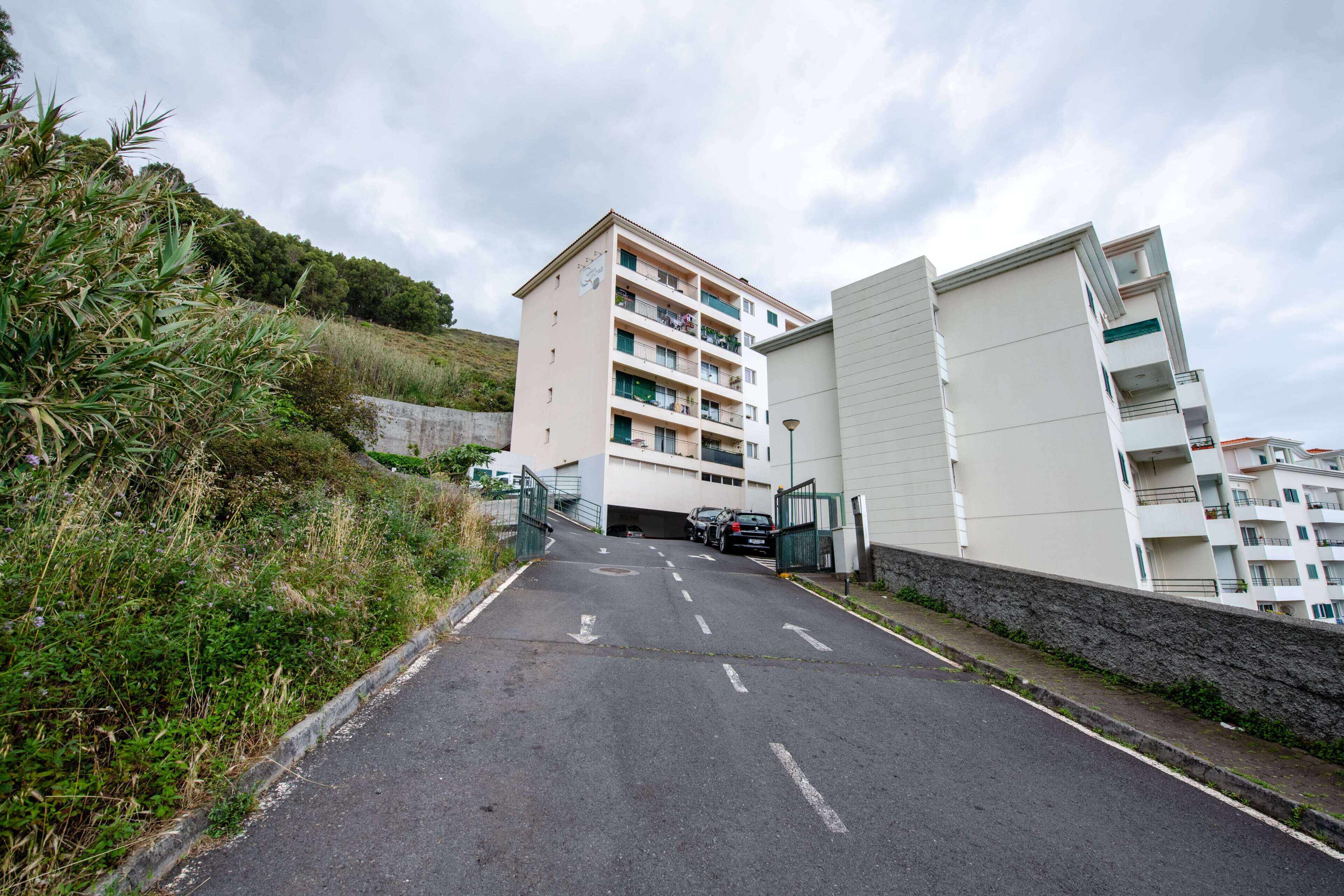 Een meerhoog appartementencomplex met een parkeerplaats ervoor.