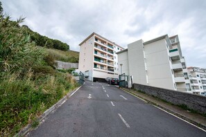 A multi-story residential building with a parking area in front. - Caniço Quintas III (Santa Cruz)