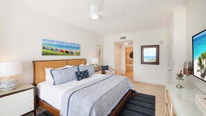 A bedroom with a bed, nightstands, a dresser, and a television.