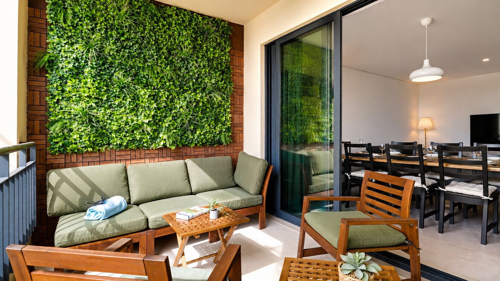 A modern living area with a green wall, a sofa, and a dining table with chairs.