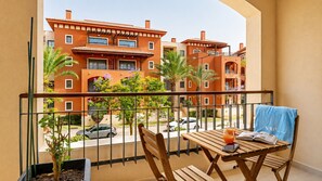 A balcony with a wooden table, chairs, and a blue towel.
