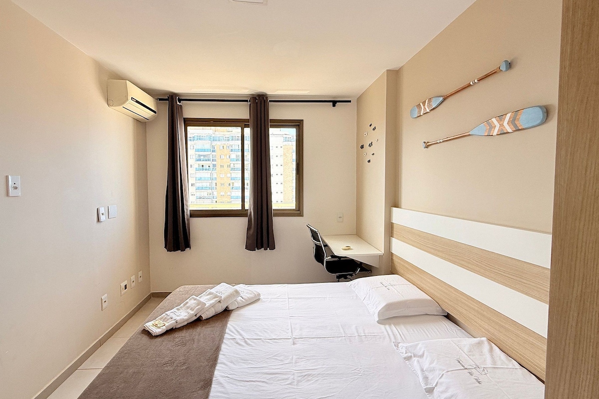 A hotel room with a bed, a desk, and a window.