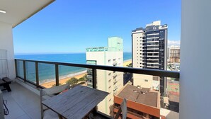 Un balcon avec vue sur l’océan et les bâtiments.