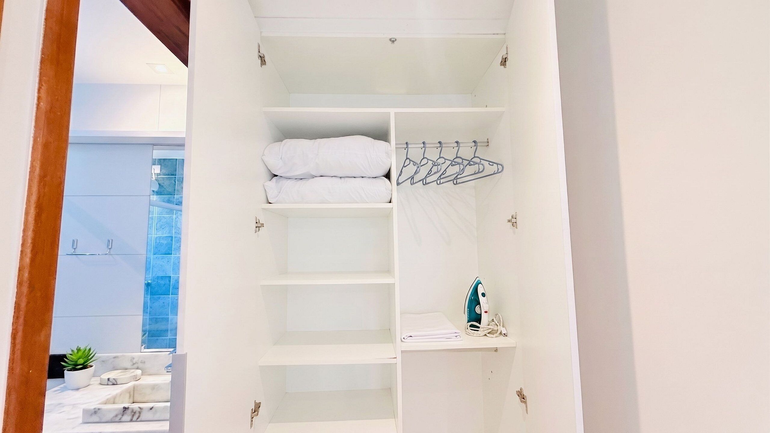 Un placard blanc avec des étagères, une tringle pour suspendre les vêtements et une serviette pliée.