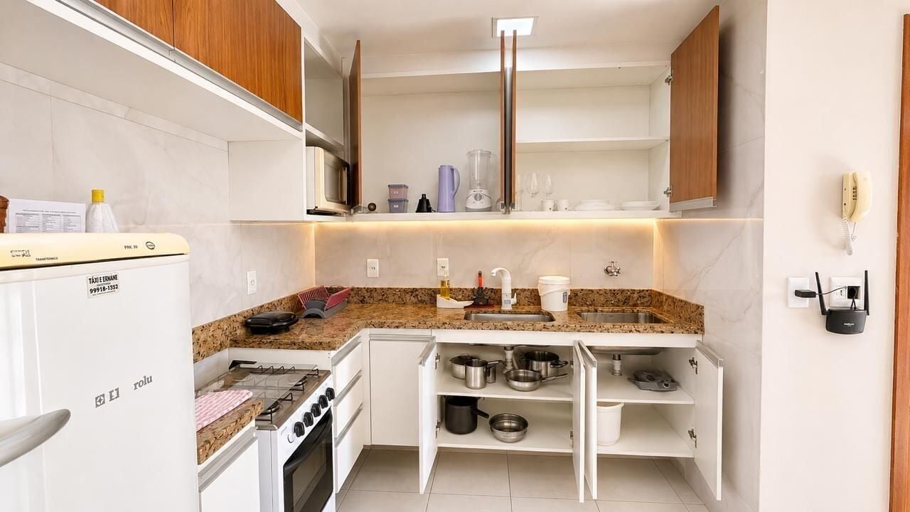 Una cocina compacta con horno integrado, un lavabo y una encimera con distintos utensilios de cocina.