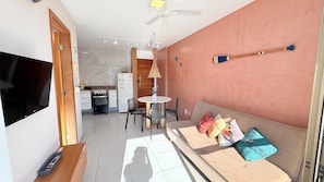 A living room with a sofa, TV, and a dining area with a table and chairs. - Praia Dourada (Vila Velha)
