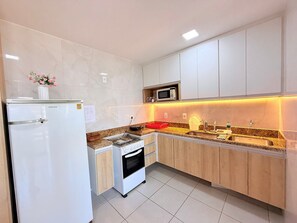 Cocina moderna con refrigerador, microondas, horno y encimera de granito.