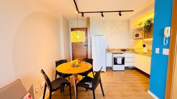 Una cocina compacta con comedor, refrigerador, microondas y estufa.