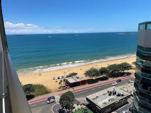 Vista costeira com praia, oceano e estrada com veículos.