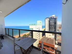 A balcony with a view of the ocean and buildings. - Praia Dourada (Vila Velha)