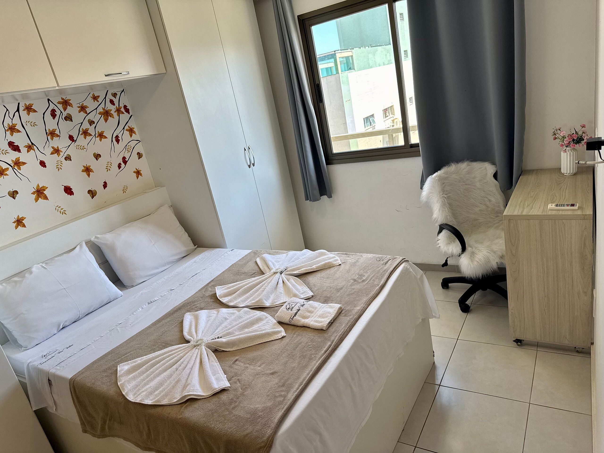 A hotel room with a bed, a desk, a chair, and a window with curtains.