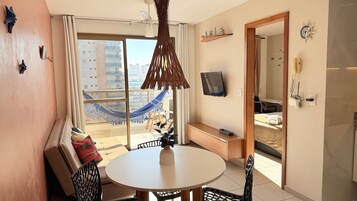 Un apartamento moderno con balcón, comedor, televisor y baño.