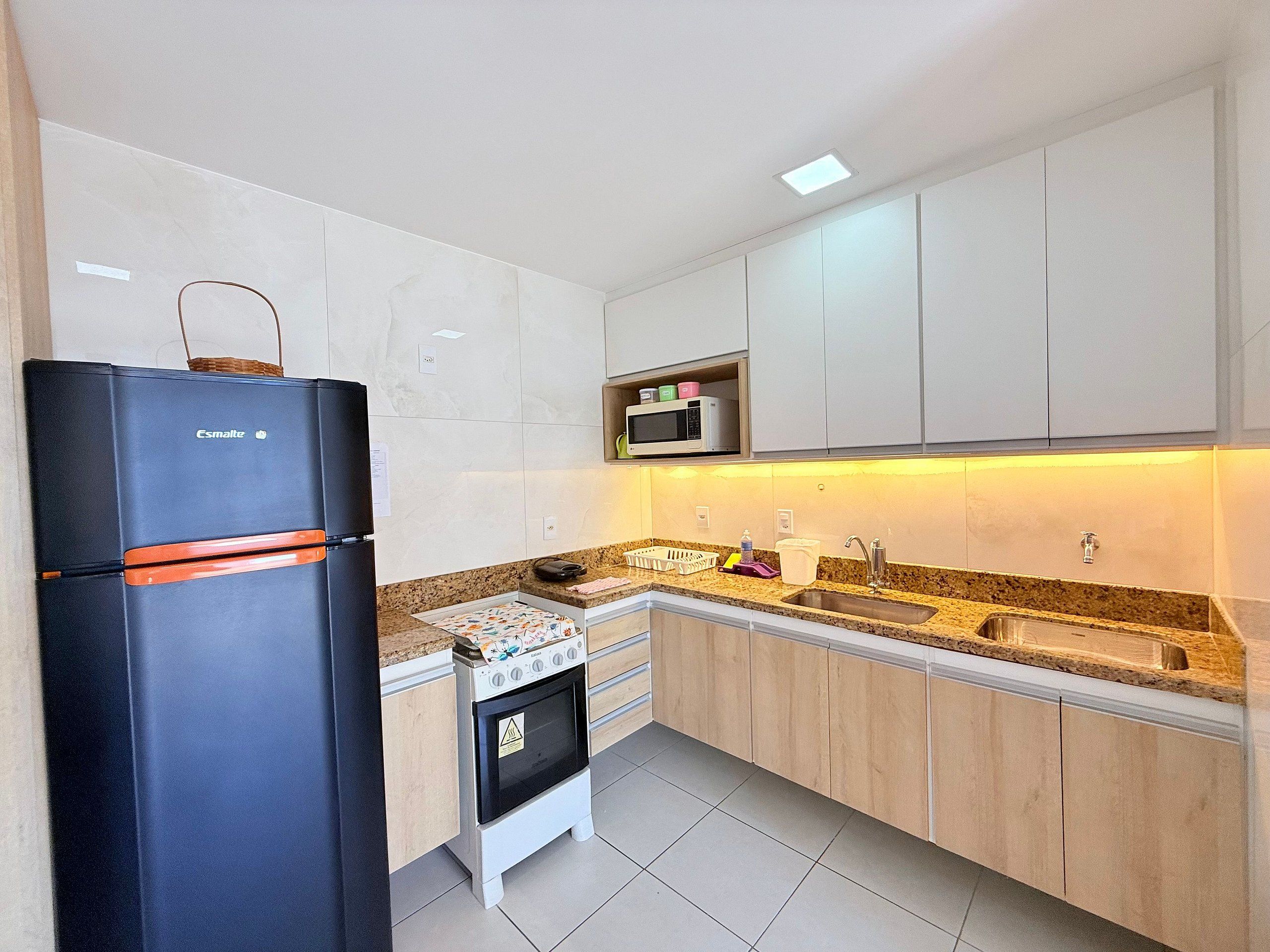 A modern kitchen with a black refrigerator, a microwave, and a stove.