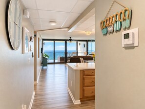 A hotel room with a view of the ocean, a large clock, and a thermostat on the wall.