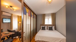 Ein Hotelzimmer mit einem Bett, einem Schreibtisch mit Stuhl, einem Fernseher und einem Fenster mit Vorhängen.