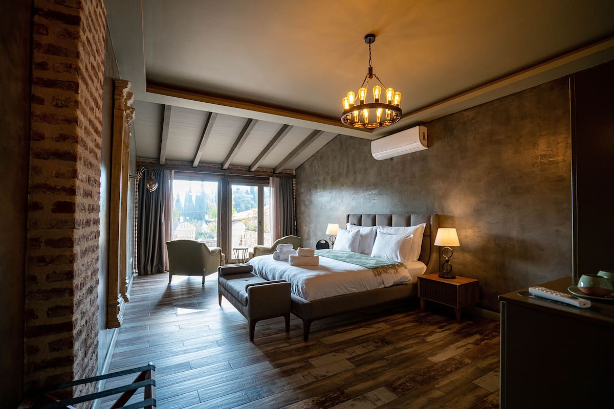 A hotel room with a large bed, a sitting area, and a view of the outdoors.