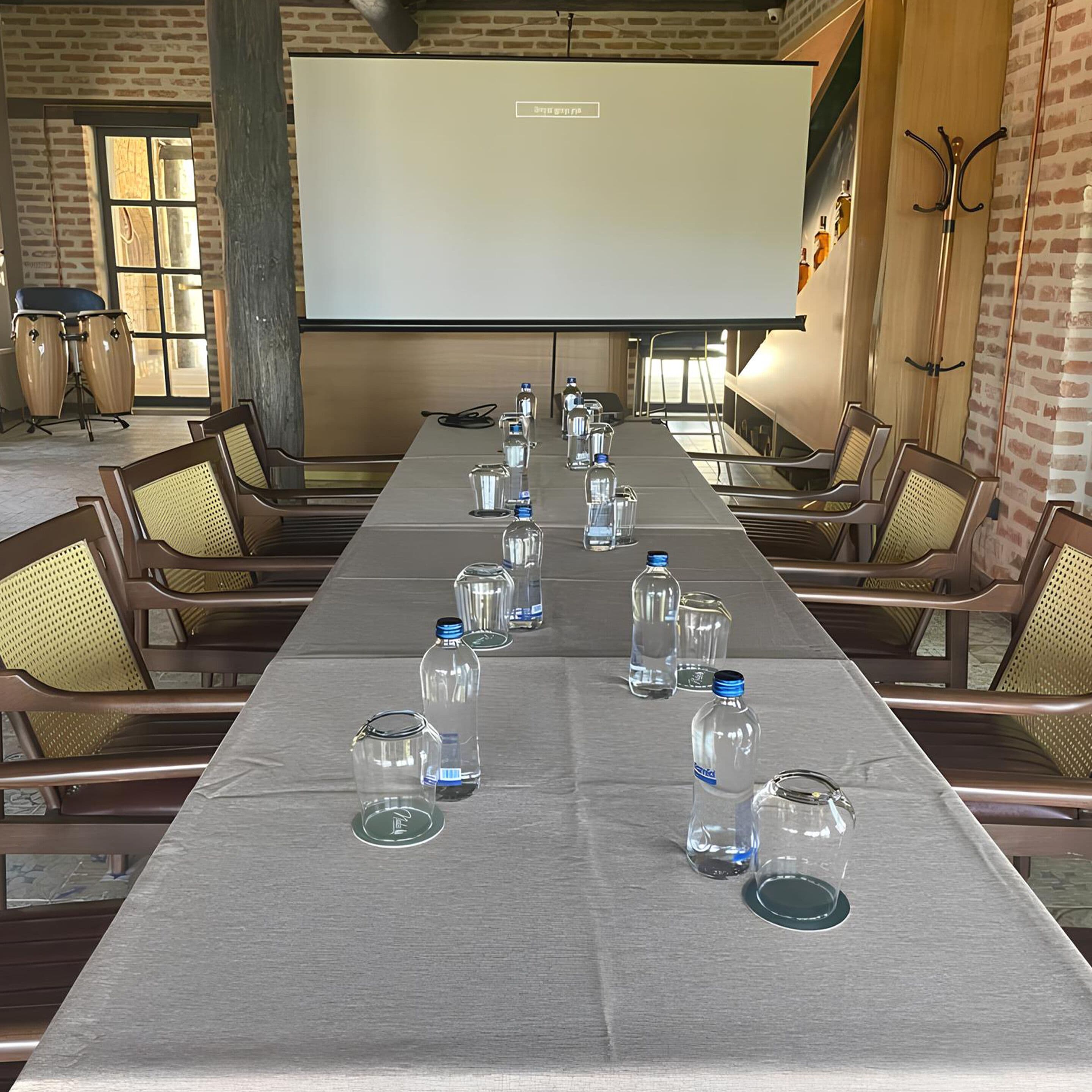 A conference room with a long table, chairs, and a projector screen.