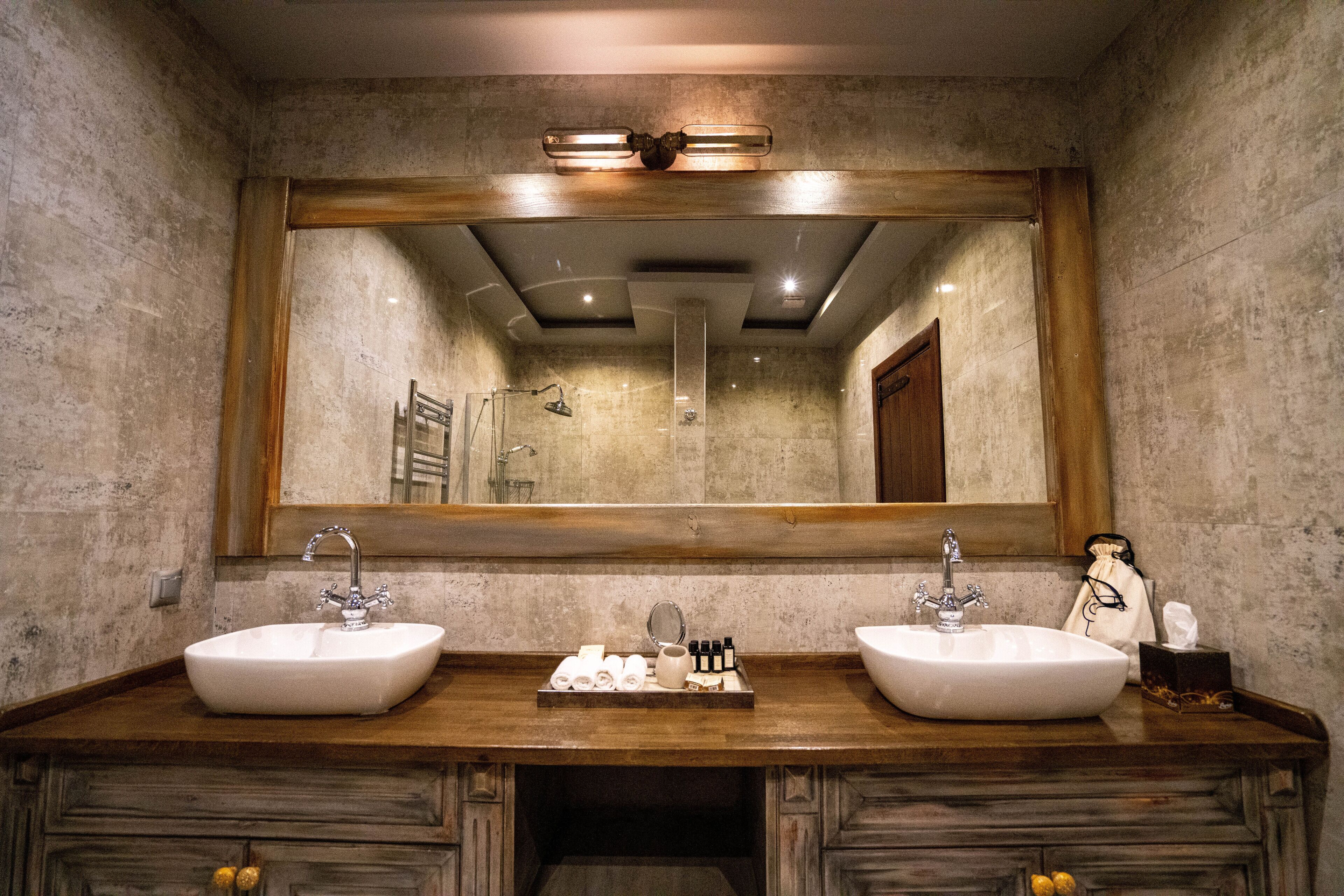 Un baño con dos lavamanos, un espejo grande y un mueble de tocador de madera.